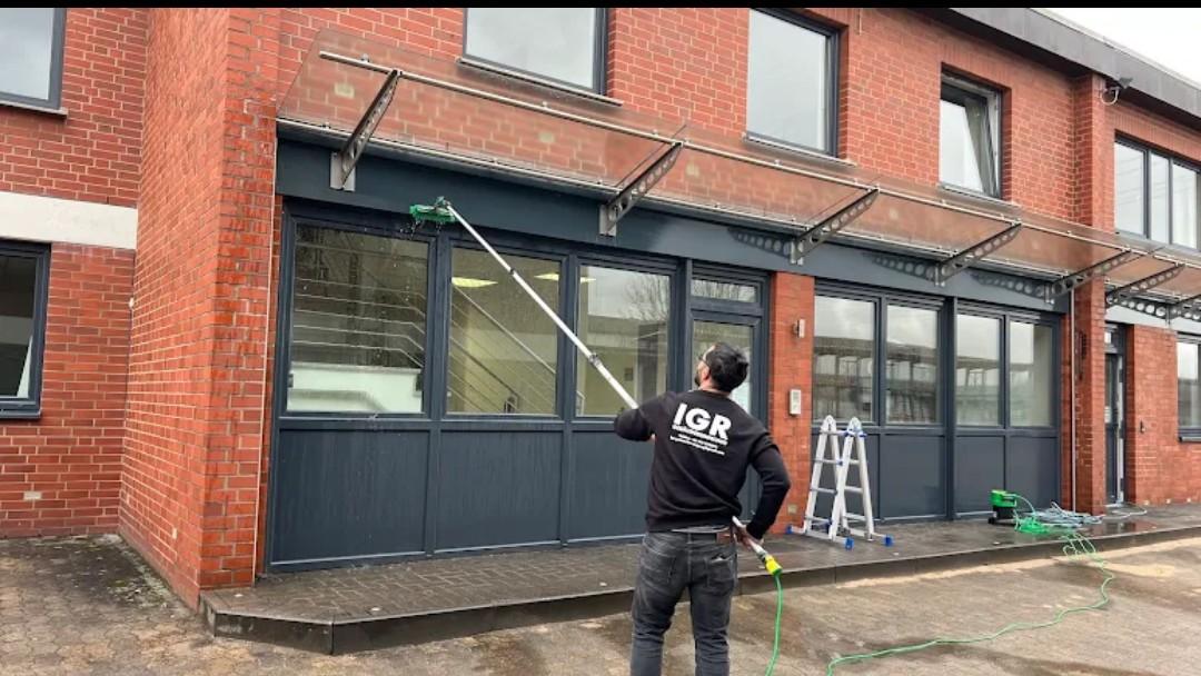 Mitarbeiter von IGR Gebäudereinigung reinigt die Fensterfront eines Gewerbeobjekts