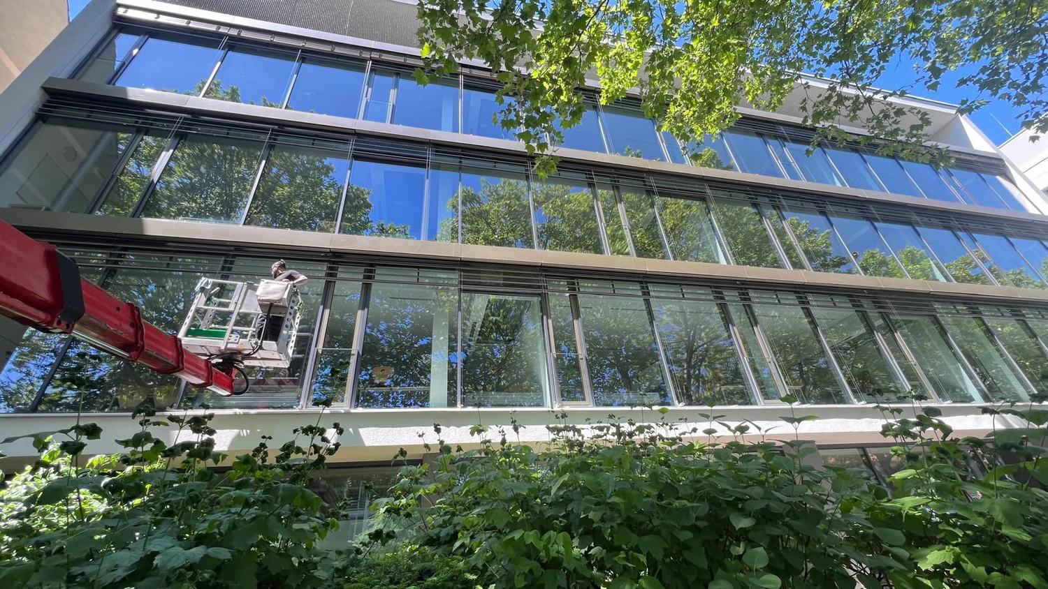 Glasfassade eines Bürogebäudes wird von der Hubarbeitsbühne gereinigt – IGR Gebäudereinigung Kalletal